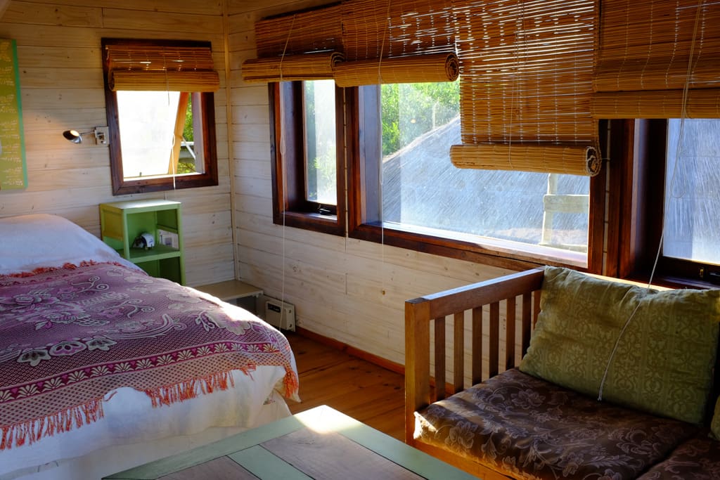 The bedroom has a double bed, mosquito net and repellent, safety box, bedside lamps, a wardrobe, table, chairs, ventilator fan and a balcony
