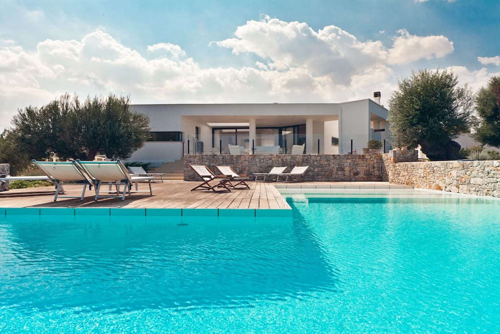 a pool with lounge chairs and a stone wall